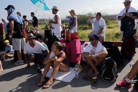 Stranded tourists stand as they wait for a Mexican Army plane that will transport them, outside the international airport in San Jose del Cabo after Hurricane Odile hit in Baja California, September 18, 2014. REUTERS/Henry Romero