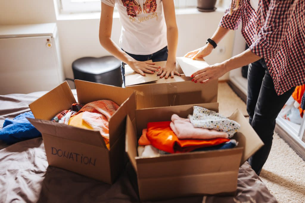 People fold clothes and put them in donation boxes. 