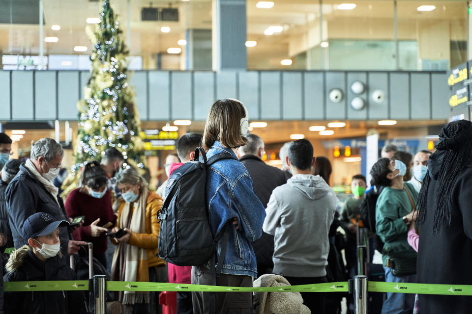 Valencia, Spain: January 5th 2021; Covid Christmas travel concept. Line of people with suitcases with Christmas tree in background