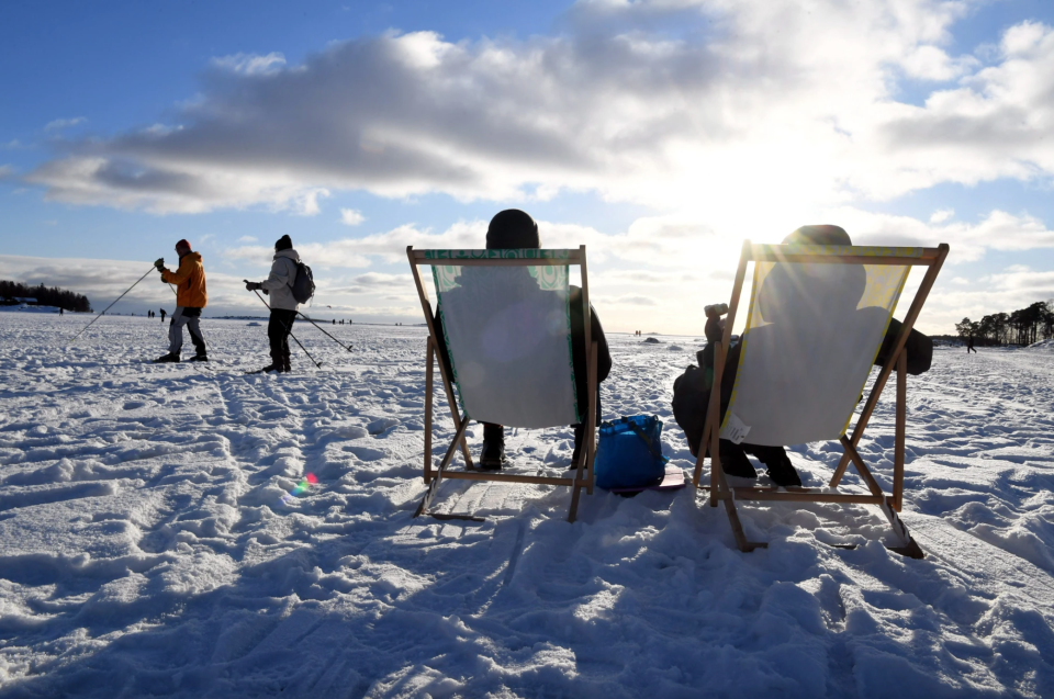 Besucher und Besucherinnen genießen das sonnige Wetter auf dem Eis im Hafen von Helsinki, Finnland, im Jahr 2021. - Copyright: Jussi Nukari / Lehtikuva / AFP via Getty Images