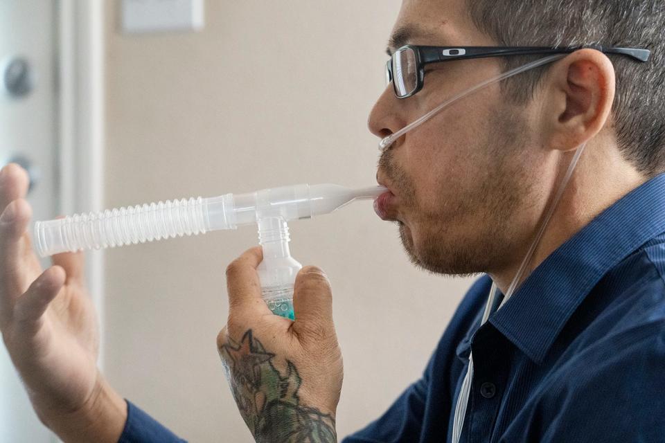 In this file photo, a man diagnosed with lung cancer, which has spread to his brain, uses his nebulizer at his home on Thursday, Oct. 12, 2023.