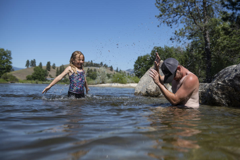 Leighanna Bardgett, 7, splashes her father Jessuah, right, as they cool off in the Bitterroot River as temperatures reached over 100 degrees in Missoula, Montana, on Wednesday, June 30, 2021. (AP Photo/Tommy Martino)