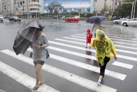 Pedestrians hold their umbrellas against strong wind as Typhoon Chan-Hom hits Shanghai, China, July 11, 2015. REUTERS/Stringer