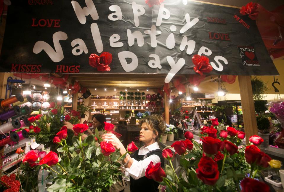 Floral designer Zetia Bradley prepares a bouquet of roses at Safeway. About $2.1 billion will be spent on flowers this Valentine’s Day, the National Retail Federation estimates.