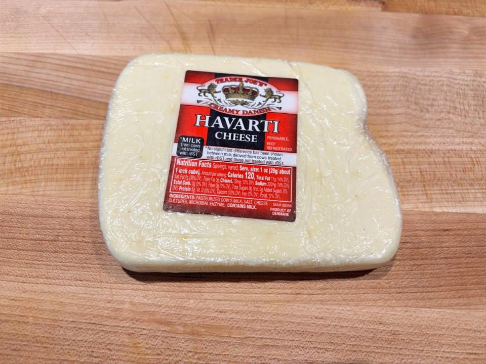 A flat, square block of white cheese with a red label reading with "Trader Joe's Havarti cheese"