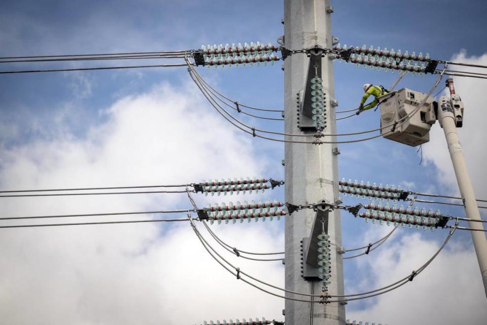 A worker for the Capital Electric Construction Co. installs transmission lines on a 100-foot-tall steel pole along 95th Street near Lexington Avenue in De Soto.