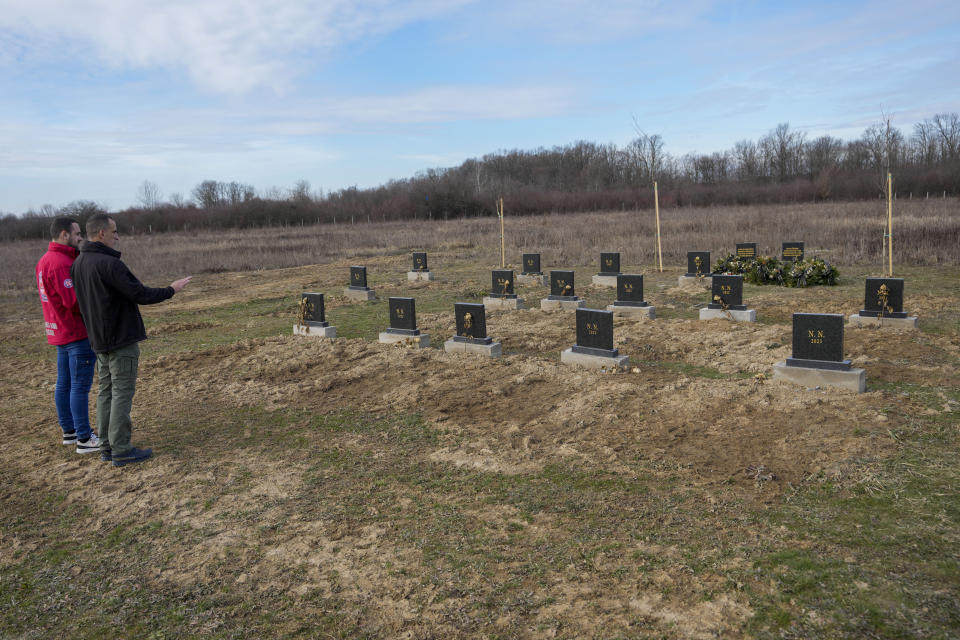 Mountain Rescue Service members Mladen Rosic, left, and Nenad Jovanovic stand by gravestones under which unidentified remains of 41 people retrieved from the river since 2017, at the cemetery in Bijeljina, eastern Bosnia, Sunday, Feb. 4, 2024. In several cities along this river between Bosnia and Serbia, simple, durable gravestones now mark the final resting places of dozens of refugees and migrants who drowned in the area while trying to reach Western Europe. (AP Photo/Darko Vojinovic)