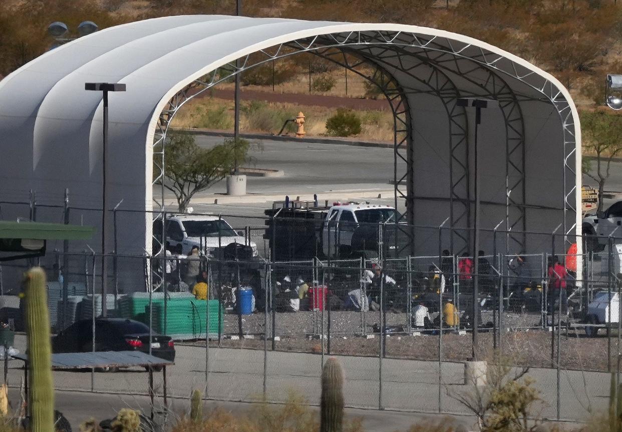 People are seen congregated in an outdoor shelter outside of the Ajo Border Patrol Station.
