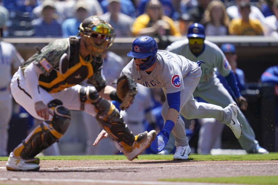 Chicago Cubs' Nico Hoerner, center, slides into home, scoring off a single by Ian Happ and a throwing error by San Diego Padres third baseman Manny Machado as Padres catcher Austin Nola waits for the throw during the first inning of a baseball game Sunday, June 4, 2023, in San Diego. (AP Photo/Gregory Bull)