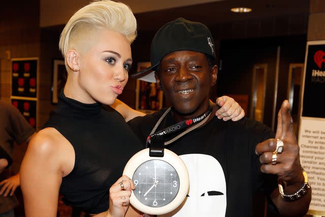 <p>Isaac Brekken/Getty Images for Clear Channel)</p> Miley Cyrus and Flavor Flav