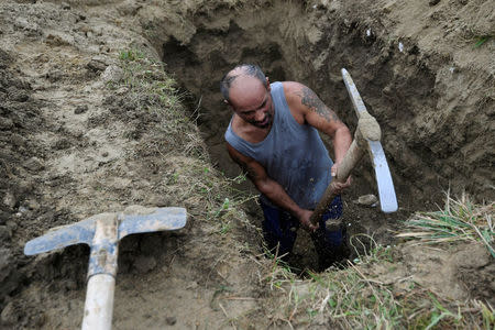 A gravedigger competes in a grave digging championship in Trencin, Slovakia, November 10, 2016, where eleven pairs of gravediggers are competing in digging based on accuracy, speed, and aesthetic quality. REUTERS/Radovan Stoklasa