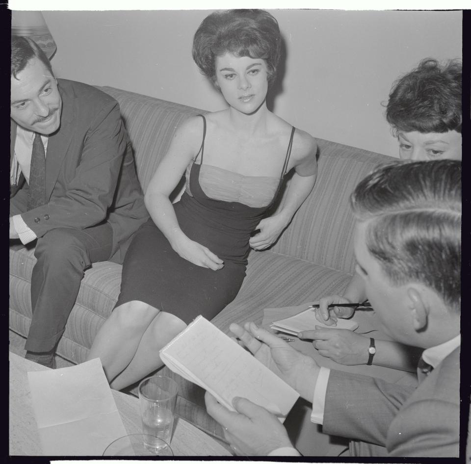 Actress Gail Ganley, 23, sits on a couch surrounded by reporters during an interview