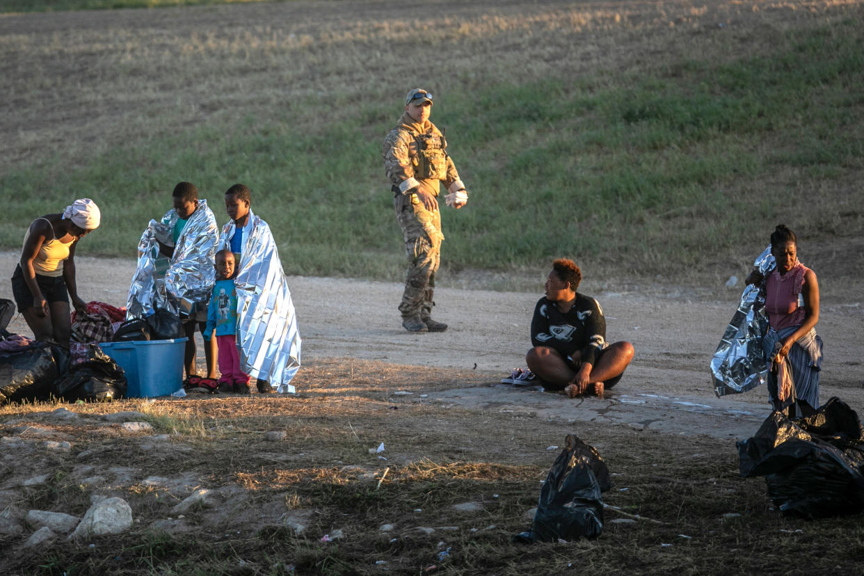 A U.S. Border Patrol agent on Thursday passes Haitian immigrant families who have crossed the Rio Grande to Del Rio, Texas, from Ciudad Acuna, Mexico.