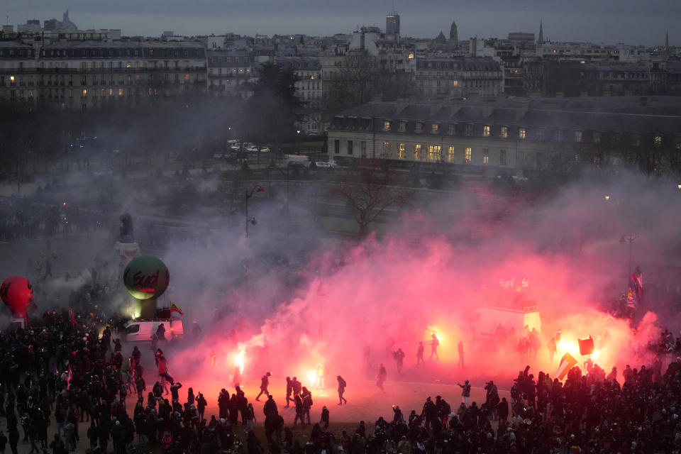 Protestors walk through flares smoke at the end of the demonstration against plans to push back France's retirement age, Tuesday, Jan. 31, 2023 in Paris. Labor unions aimed to mobilize more than 1 million demonstrators in what one veteran left-wing leader described as a "citizens' insurrection." The nationwide strikes and protests were a crucial test both for President Emmanuel Macron's government and its opponents. (AP Photo/Thibault Camus)