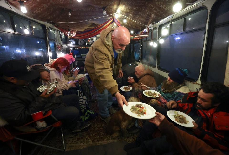 Volunteer Robert Loard serves dinner to unsheltered people staying on the Nomad Alliance bus.