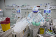 A member of the medical staff prepares to shave a patient in the COVID-19 ICU unit of the Marius Nasta National Pneumology Institute in Bucharest, Romania, Thursday, Sept. 23, 2021. Daily new coronavirus infections in Romania, a country of 19 million, have grown exponentially over the last month, while vaccine uptake has declined to worrying lows. Government data shows that 91.5% of COVID-19 deaths in Romania between Sept. 18-23 were people who had not been vaccinated. (AP Photo/Vadim Ghirda)