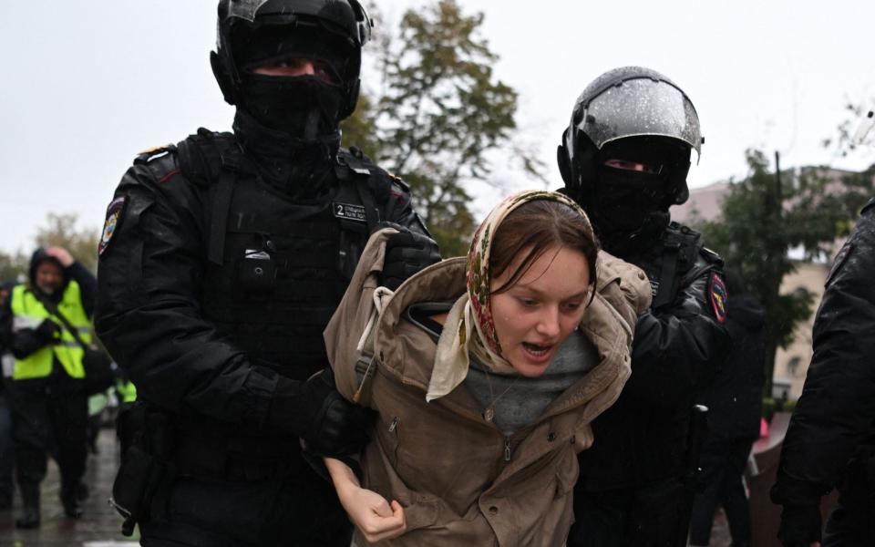 Police officers detain a woman in Moscow following protests - AFP