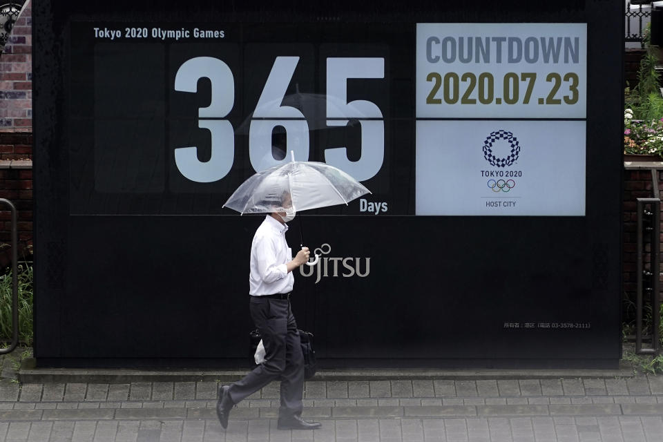 A man wearing a mask against the spread of the new coronavirus walks in front of a countdown calendar showing 356 day to start Tokyo 2020 Olympics Thursday, July 23, 2020, in Tokyo. The postponed Tokyo Olympics have again reached the one-year-to-go mark. But the celebration is small this time with more questions than answers about how the Olympics can happen in the middle of a pandemic. That was before COVID-19 postponed the Olympics and pushed back the opening to July 23, 2021. (AP Photo/Eugene Hoshiko)