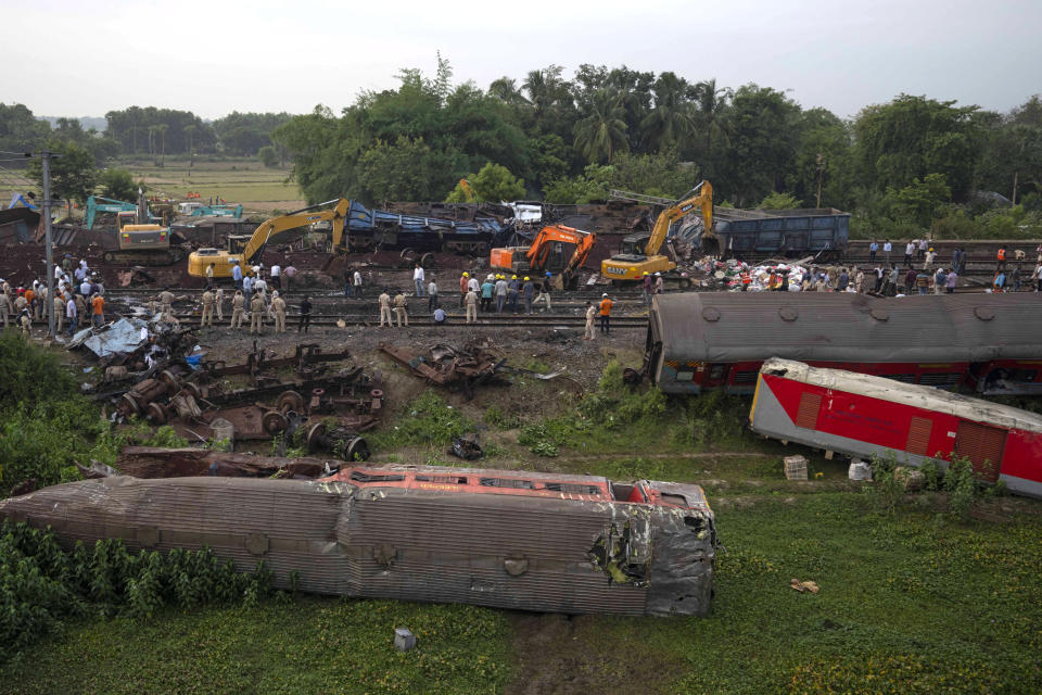 People watch at the site where trains that derailed, in Balasore district, in the eastern Indian state of Orissa, Sunday, June 4, 2023. Indian authorities end rescue work and begin clearing mangled wreckage of two passenger trains that derailed in eastern India, killing over 300 people and injuring hundreds in one of the country’s deadliest rail crashes in decades. (AP Photo/Rafiq Maqbool)