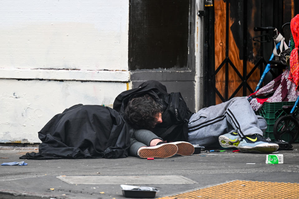 A homeless couple sleeps on a sidewalk in San Francisco.