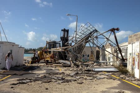 A woman walks around debris after Hurricane Gonzalo passed through the Royal Naval Dockyard, western Bermuda, October 18, 2014. REUTERS/Nicola Muirhead