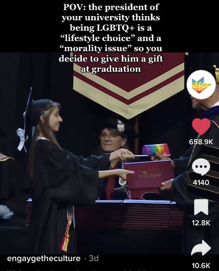 A sixth student with a pride flag at graduation