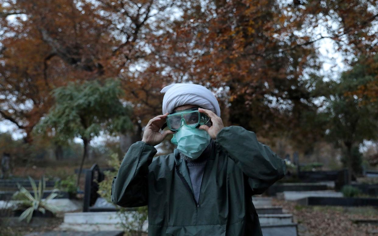 Ali Rahimi, 53, a volunteer cleric wearing protective clothing prepares for a funeral - Ebrahim Noroozi