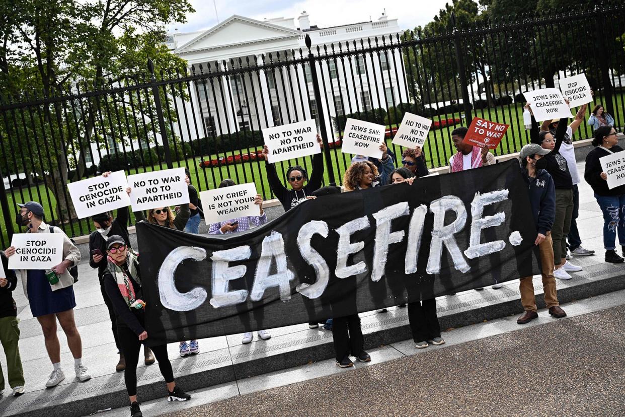 Protesters in front of the White House hold a big sign reading CEASEFIRE, with smaller signs held around it: "Stop Genocide in Gaza"; "No to War, No to Apartheid"; "My Grief Is Not Your Weapon"; "Jews Say Ceasefire Now"; and others.