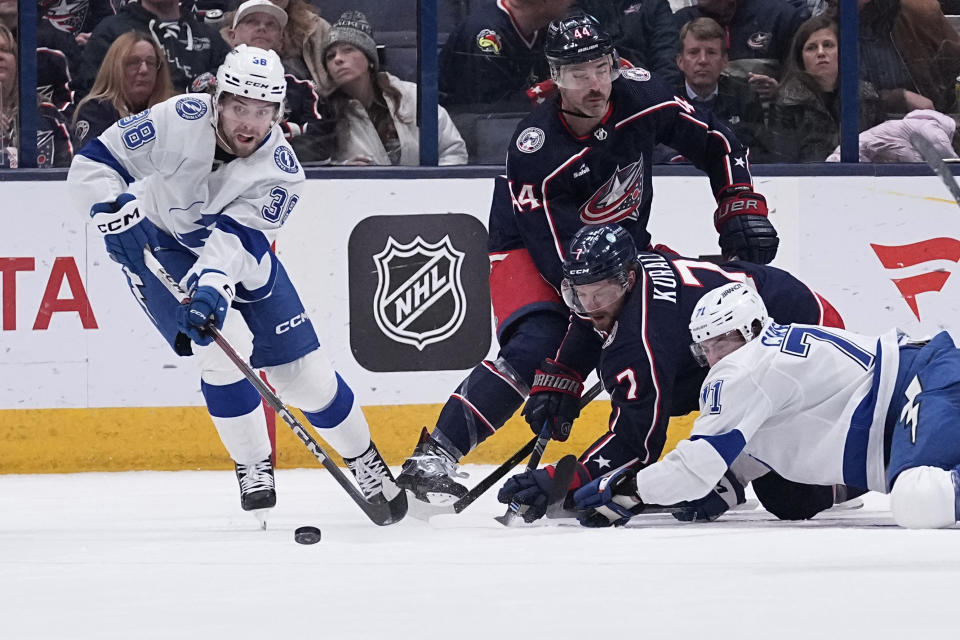 Tampa Bay Lightning left wing Brandon Hagel (38) skates away from Columbus Blue Jackets' Sean Kuraly (7) and Lightning's Anthony Cirelli (71) with the puck in the second period of an NHL hockey game Thursday, Nov. 2, 2023, in Columbus, Ohio. (AP Photo/Sue Ogrocki)