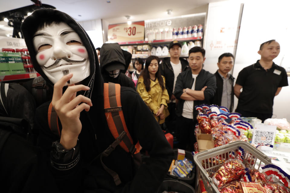 Protesters gather near shoppers in a store at a mall popular with traders from mainland China near the Chinese border in Hong Kong, Saturday, Dec. 28, 2019. Protesters shouting "Liberate Hong Kong!" marched through a shopping mall Saturday to demand that mainland Chinese traders leave the territory in a fresh weekend of anti-government tension. (AP Photo/Lee Jin-man)