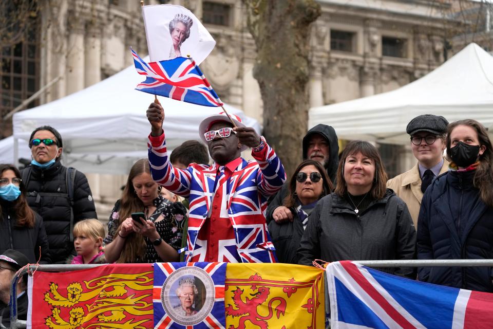 Royal fans wave a flag showing Queen Elizabeth II as crowds gathered ahead of a service of thanksgiving for the life of her late husband, Prince Philip, Duke of Edinburgh, at Westminster Abbey in London, March 29, 2022.