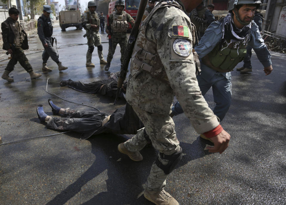 Afghan Army and police men drag a killed suicide bomber from the scene after the Taliban staged a multi-pronged attack on a police station in Jalalabad, eastern Afghanistan, Thursday, March 20, 2014. The hours-long assault was the latest in the countdown to next month's presidential elections. (AP Photo/Rahmat Gul)