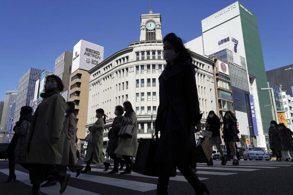 People wearing protective masks to help curb the spread of the coronavirus walk along a pedestrian crossing Wednesday, March 3, 2021, in Tokyo. The Japanese capital confirmed more than 310 new coronavirus cases on Wednesday. (AP Photo/Eugene Hoshiko)