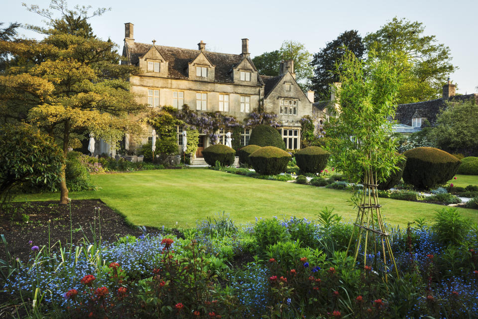 Exterior view of a 17th century country house from a garden with flower beds, shrubs and trees. Photo: Getty