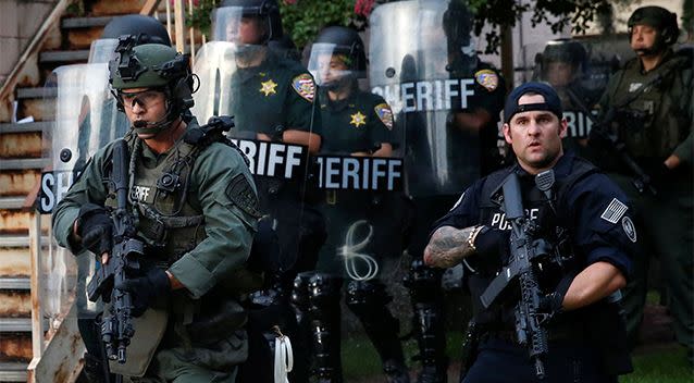 Officers march down a street during protests in Baton Rouge. Photo: Reuters/Shannon Stapleton