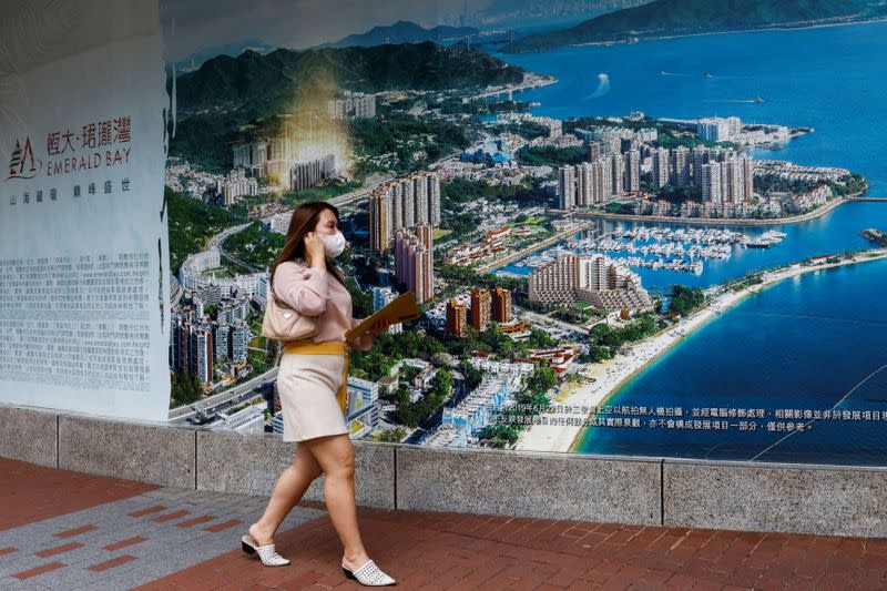 A woman walks past a property advertisement in Hong Kong