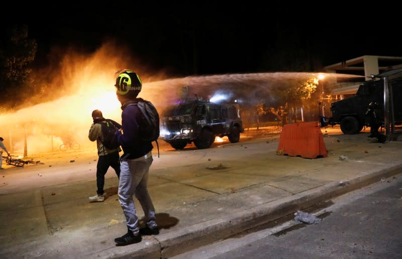 A riot police vehicle fires water cannon during a protest at the National University as a national strike continues in Bogota