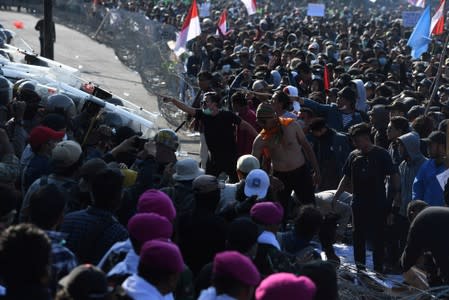 Protesters gesture to riot police officers during a protest in Surabaya