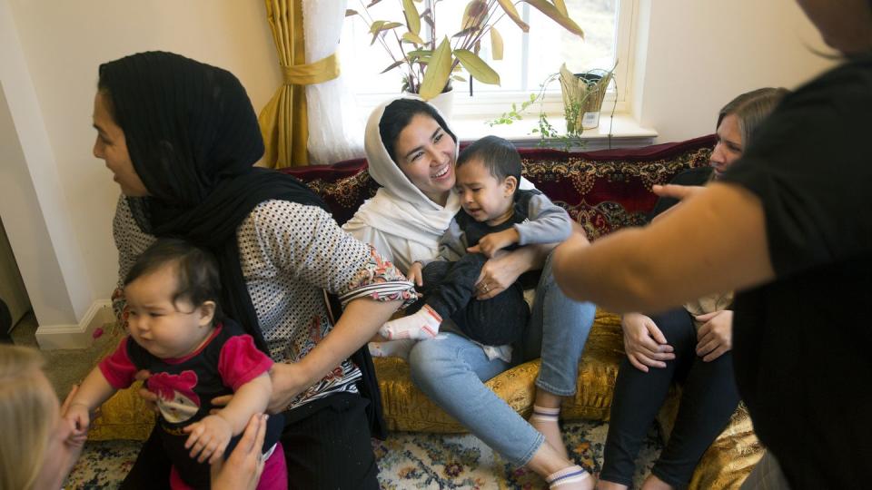 Sima Gul, center, holds her son, Amir Mazlom Yar, as Azizgul Ahmadi, right, reaches for him during a gathering at her home, welcoming Gul to Blacksburg, Va., on Dec.9, 2022. (Heather Rousseau/The Roanoke Times via AP)