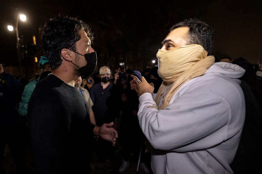 A pro-Palestinian protester (L) and a counter protester talk amid clashes at a pro-Palestinian encampment set up on the campus of the University of California Los Angeles (UCLA), in Los Angeles on May 1, 2024.