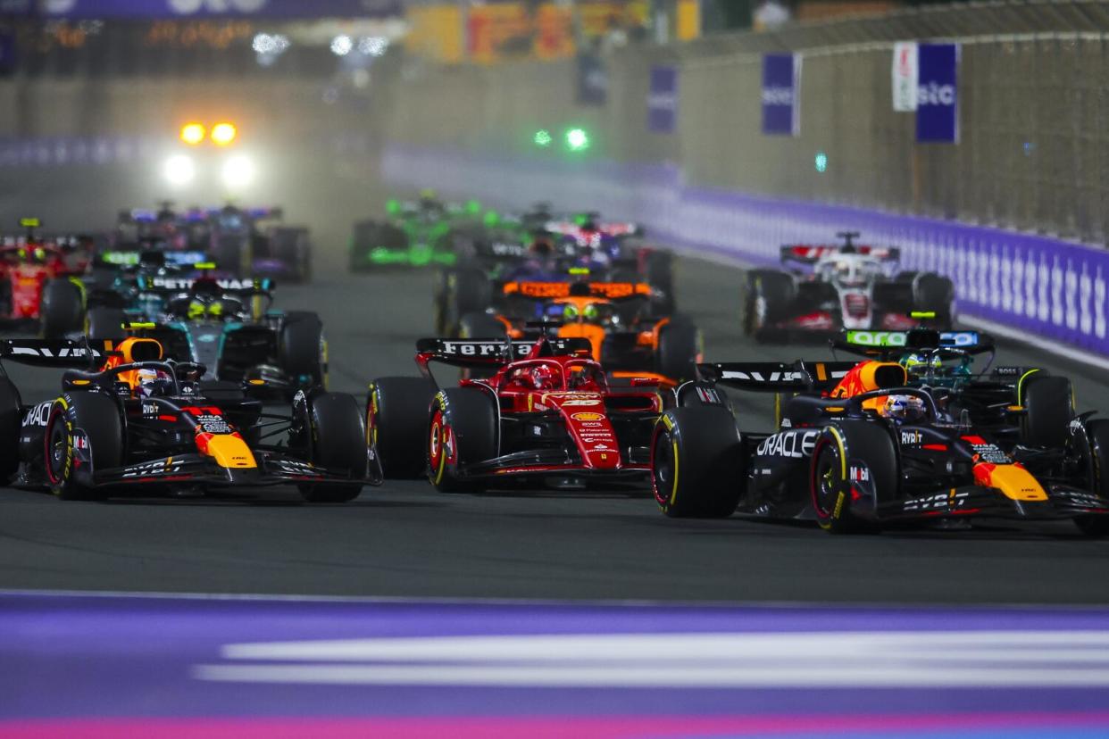 Formula One drivers race in close quarters on a track.