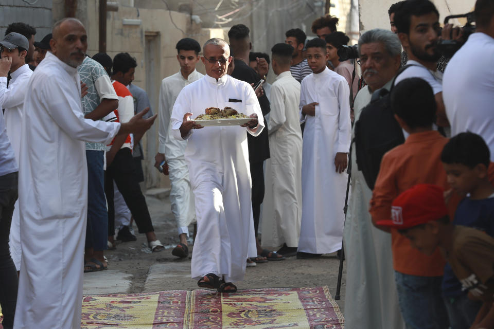 Iraqis eat morning breakfast on the first day of Eid Al-Fitr holiday in Basra, Iraq, Friday, April 21, 2023. Eid Al-Fitr marks the end of the Muslim holy fasting month of Ramadan. (AP Photo/Nabil al-Jurani)