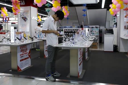 A customer look at a mobile phone on display at an electronics market in Shanghai, China, June 24, 2015. Picture taken June 24, 2015. REUTERS/Aly Song