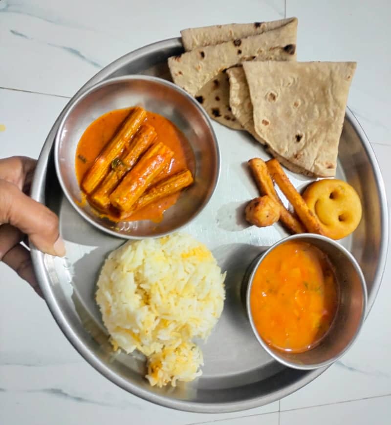 drumstick curry paired with dal fry, served alongside wheat flour tortillas, plain rice, and fried McCain variety potato chunks