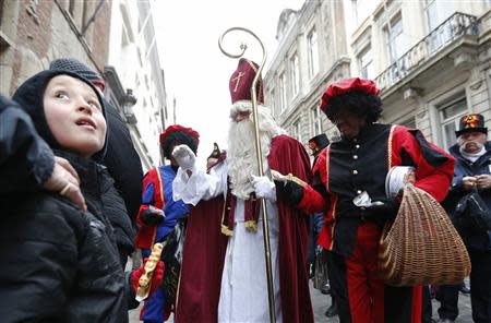 Saint Nicholas (C) is escorted by his assistants called "Zwarte Piet" (Black Pete) during a traditional parade in central Brussels in this December 1, 2012 file photo. REUTERS/Francois Lenoir/Files