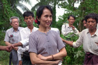 FILE - Nobel Peace Prize winner Aung San Suu Kyi is surrounded by bodyguards and aides in the garden of her house during a press conference following her release earlier in the week after six years under house arrest, Rangoon, Burma on July 14, 1995. Myanmar court on Monday, Dec. 6, 2021, sentenced ousted leader Suu Kyi to 4 years for incitement and breaking virus restrictions then later in the day state TV announced that the country's military leader reduced the sentence by two years. (AP Photo/Anat Givon, File)