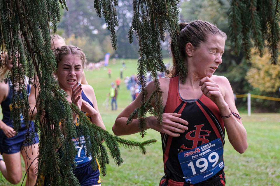 Clara Fletcher (199) from St. Johns and others are suprised by over-hanging branches in the D2 cross country regional race Friday, Oct. 29, 2021 at St. Francis Retreat Center in DeWitt.