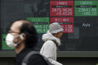 People walk past an electronic stock board showing Japan's Nikkei 225 index and other Asian country index at a securities firm in Tokyo Monday, Feb. 10, 2020. Asian stock markets slid Monday after China reported an uptick in new cases of its virus outbreak and analysts warned optimism the disease is under control might be premature. (AP Photo/Eugene Hoshiko)