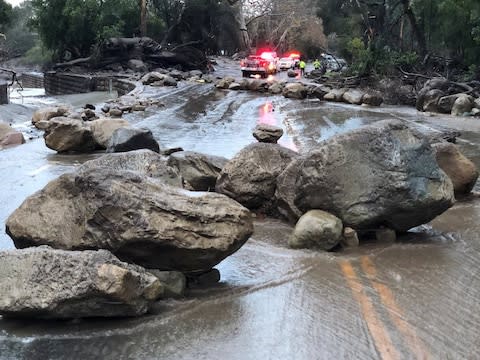 Boulders block a road after being moved by the mudslide - Credit: Reuters