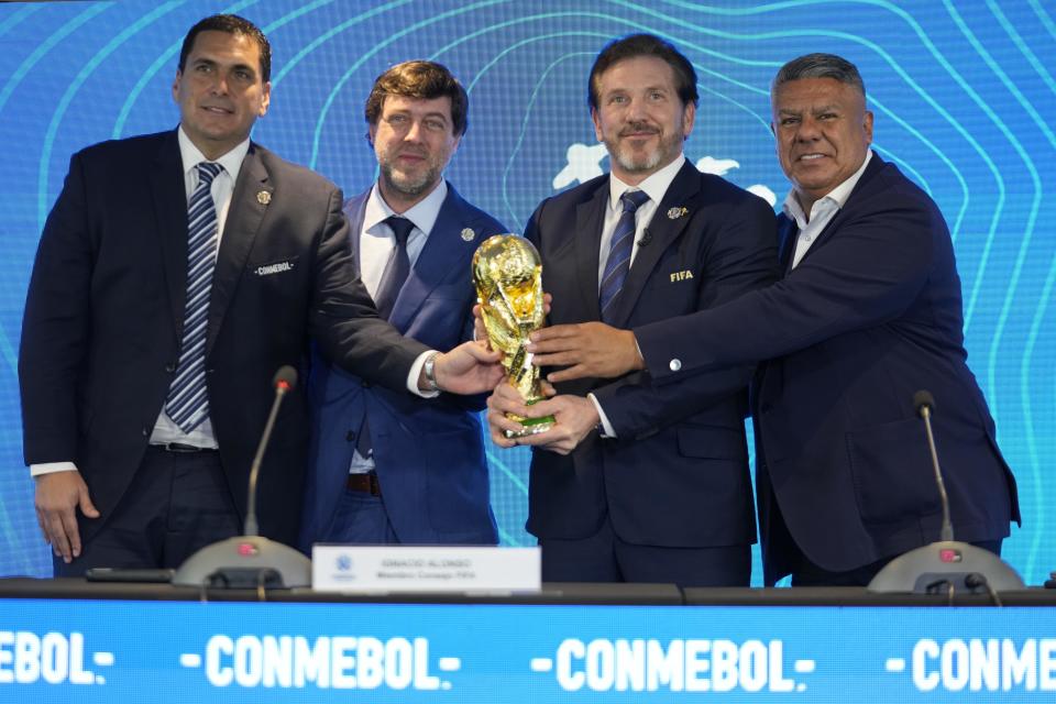 El presidente de la federación de Paraguay Robert Harrison (izquierda), el presidente de la federación de Uruguay Ignacio Alonso (centro), el presidente de la CONMEBOL Alejandro Domínguez (tercero a la izquierda y el presidente de la federación de Argentina Claudio Tapia sostiene el trofeo de la Copa Mundial durante una rueda de prensa, el miércoles 4 de octubre de 2023, en Luque, Paraguay. Domínguez anunció que los partidos inaugurales del Mundial 2030 se jugarán en Argentina, Uruguay y Paraguay. (AP Foto/Jorge Sáenz)